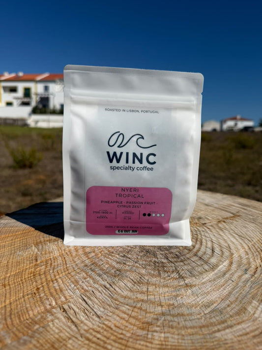 Saco branco de café Winc Nyeri Tropical do Quénia, com rótulo rosa, sobre uma superfície de madeira